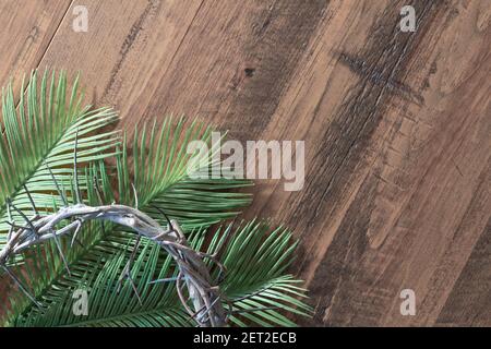 Dornenkrone auf Palmwedeln auf dunklem Holz mit Speicherplatz kopieren Stockfoto