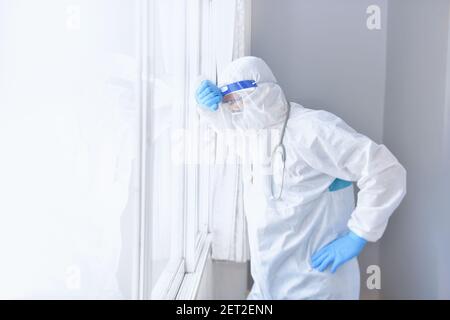 Müde Arzt mit PSA gegen ein Fenster lehnend, Thailand Stockfoto