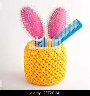Handgefertigter gelber Korb mit Massage-Haarkämmen. Textur aus gestrickten Stoffflechten. Stockfoto
