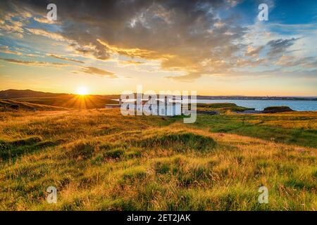 Dramatischer Sonnenuntergang über den alten Küstenhütten am Arnish Point Am Eingang zum Stornoway Hafen an der Ilse of Lewis auf den westlichen Inseln von SCO Stockfoto