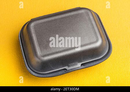 Schwarze geschlossene Styropor-Box auf gelbem Hintergrund Stockfoto