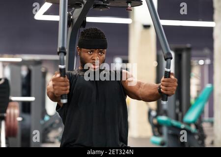 Junge schwarze Sportler trainieren Muskeln auf Block exerciser in der Turnhalle Stockfoto