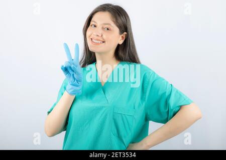 Porträt einer jungen Ärztin in grüner Uniform Siegeszeichen Stockfoto