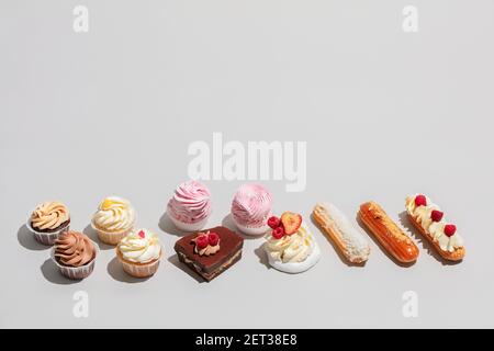 Süßes Dessert in zwei Reihen auf grauem Hintergrund komponiert. Süßes Gebäck. Flach liegend, Copyspace. Stockfoto