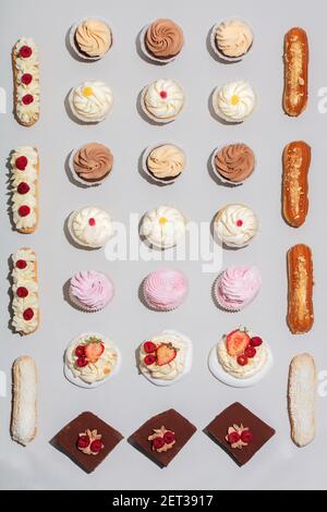 Dekorierte Kuchen in geometrischer Komposition auf grauem Hintergrund. Süße Desserts. Flach liegend. Stockfoto