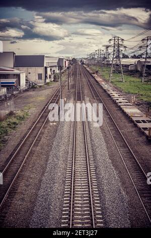 Eisenbahnlinien und Hochspannungsleitungen unter dramatischem Himmel; Instagram-Filter. Stockfoto
