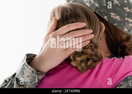 Mutter in Militäruniform umarmende Kind auf weiß isoliert Stockfoto