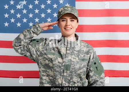 Lächelnder Soldat, der im Hintergrund neben der amerikanischen Flagge grüsst Stockfoto