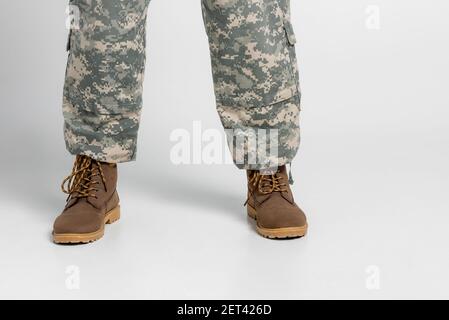 Verkürzte Ansicht des Soldaten in Militärhose und Stiefeln Grauer Hintergrund Stockfoto