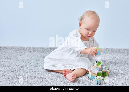 Kleines Mädchen baut eine Pyramide aus Holzblöcken auf dem Teppich. Speicherplatz kopieren Stockfoto