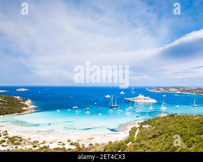 Blick von oben, atemberaubende Luftaufnahme des Grande Pevero Strandes mit Booten und Luxusyachten, die auf einem türkisfarbenen, klaren Wasser segeln. Sardinien, Italien. Stockfoto