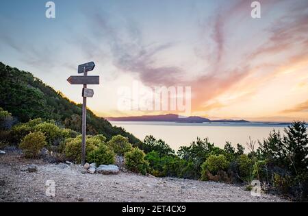 Ländliche Landschaft mit Kreuzungen auf dem Hügel bei einem schönen Sonnenuntergang. Zwei verschiedene Richtungen. Konzept der Wahl der richtigen Art und Weise. Stockfoto