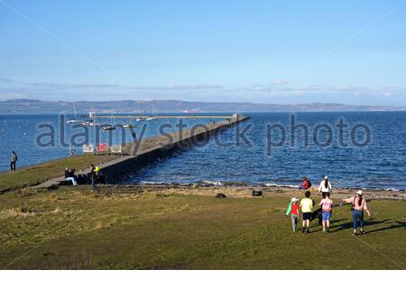 Edinburgh, Schottland, Großbritannien. März 2021, 1st. Menschen genießen die Natur an Wardie Bay Waterfront, Granton Hafen und Wellenbrecher an einem kühlen und sonnigen Nachmittag. Blick über die vierte Mündung nach Norden in Richtung Fife. Kredit: Craig Brown/Alamy Live Nachrichten Stockfoto