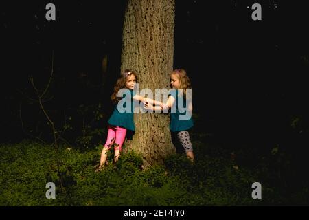 Zwei Mädchen stehen in einem Garten in der Nacht umarmt einen Baum, Polen Stockfoto