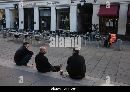 Glasgow, Großbritannien, am 1. März 2021. Während der letzten Sperre sitzen Arbeiter mit ihrem Kaffee auf dem Bürgersteig, neben Cafés ohne Kunden, in leeren Straßen im Stadtzentrum. Mehr als 1,5 Millionen Menschen haben jetzt ihre erste Covid-19-Coronavirus-Impfung in Schottland erhalten. Foto: Jeremy Sutton-Hibbert/Alamy Live News. Stockfoto