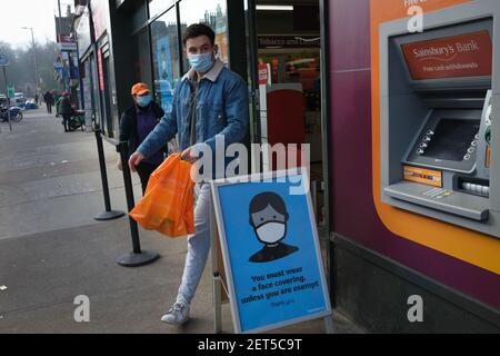 Glasgow, Großbritannien, am 1. März 2021. Inmitten ruhiger und leerer Straßen im Stadtzentrum, verlässt ein Shopper einen wichtigen Supermarkt, trägt eine Maske und vorbei an Covid-19 Coronavirus Sicherheitshinweisen, während der letzten Sperre. Mehr als 1,5 Millionen Menschen haben jetzt ihre erste Covid-19-Coronavirus-Impfung in Schottland erhalten. Foto: Jeremy Sutton-Hibbert/Alamy Live News. Stockfoto