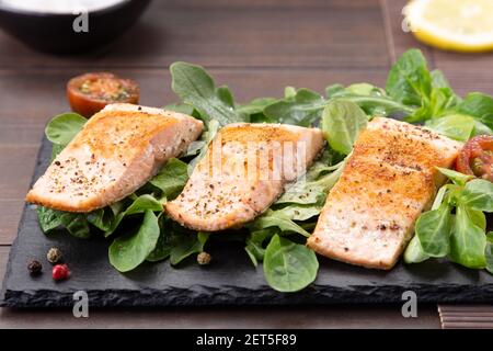 Lachsfilets auf Schieferplatte auf Holztisch Hintergrund. Stockfoto