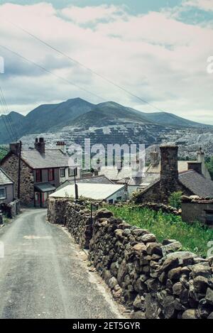 1980 Bethesda North Wales - Penrhyn Schiefersteinbruch bei Bethesda - Schrobenhaufen und Terrassen im Penrhyn Schiefersteinbruch, Bethesda, Bangor, Gwynedd, North Wales GB, UK, Europa. Industrielandschaft mit Penrhyn Schiefersteinbruch und Schotterhaufen über Häusern in Bethesda Stadt am Rande des Snowdonia National Park. Der Penrhyn Steinbruch ist ein Schieferbruch in der Nähe von Bethesda, Nordwales. Am Ende des 19. Jahrhunderts war es der größte Schieferbruch der Welt; die Hauptgrube ist fast 1 Meilen lang und 1.200 Fuß tief, und es wurde von fast 3.000 Steinbrüchen bearbeitet. Penrhyn ist immer noch Großbritanniens größter Schieferbruch Stockfoto