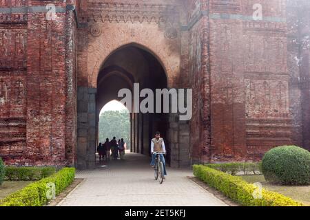 Malda, Westbengalen, Indien - Januar 2018: Ein indischer Mann, der mit dem Fahrrad im alten Tor der Baro Shona Masjid Moschee im Dorf fährt Stockfoto