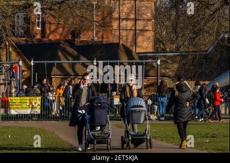 London, Großbritannien. März 2021, 1st. Spielplätze sollen eigentlich nur für Leute ohne Garten sein, sind aber voll - es ist sonnig, aber kalt und die Leute treffen sich immer noch mit Freunden und/oder bekommen etwas Bewegung. Outdoor-Leben auf Clapham Common in Lockdown 3, die einen Aufenthalt zu Hause Unterricht beinhaltet. Kredit: Guy Bell/Alamy Live Nachrichten Stockfoto