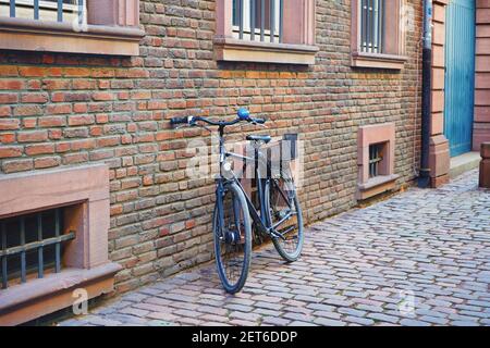 Typische alte Straße in der historischen Düsseldorfer Altstadt mit Backsteingebäude, altem Fahrrad und Kopfsteinpflaster. Retro-Filter. Stockfoto