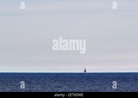 Eine schöne Aufnahme des Meeres mit einem eineineinmunchen Segelboot Segeln in der Mitte Stockfoto