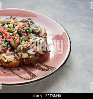 Eine köstliche Waffel serviert mit einem rosa Teller auf einem Grauer Hintergrund Stockfoto