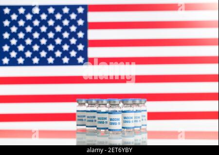 Neuer Impfstoff gegen Coronavirus, Covid, sars. Viele Flaschen mit Medikamenten mit amerikanischer Flagge im Hintergrund. Konfrontation virale Gefahr Stockfoto