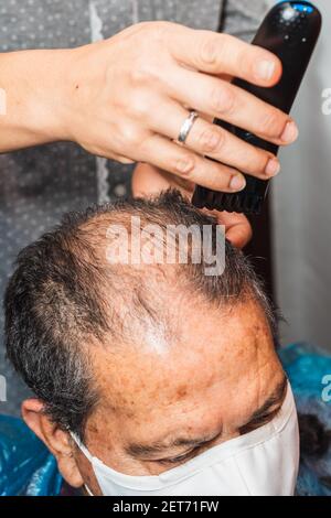 Tochter schneidet ihrem Vater die Haare zu Hause Stockfoto