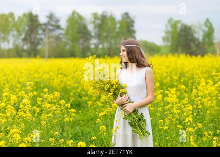 Schönes Mädchen in einem Rapsfeld. Ein Kind in einem blühenden Feld mit gelben Blüten. Plantage von gelben Blumen Stockfoto