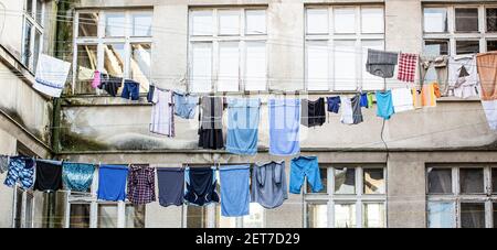 Wäsche trocknen am Seil. Gewaschene Kleidung, die außerhalb eines alten Hauses trocknet. Gewaschene Wäsche trocknen. Frische saubere Kleidung trocknet draußen. Kleidung Stockfoto