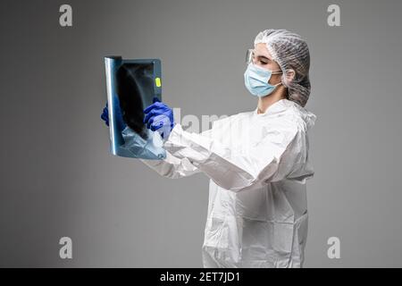 Pneumologin oder Onkologin mit Röntgenaufnahme des Brustkorbs, Untersuchung von COVID-19-Patienten Lungen, tragen PSA-Uniform, Coronavirus akute respiratorische Virus Stockfoto