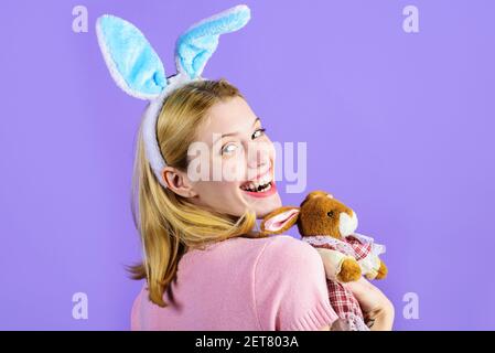 Frohe Ostern. Lächelndes Mädchen mit Plüsch Hase Spielzeug. Hübsche Frau mit Kaninchenohren. Stockfoto