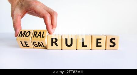 Rechtliche oder moralische Regeln Symbol. Geschäftsmann dreht Holzwürfel und ändert Wörter rechtliche Regeln zu moralischen Regeln auf einem schönen weißen Hintergrund. Business und Stockfoto