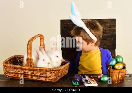 Kind in Hasenohren am Ostertag. Niedlicher Junge mit Easter Kaninchen im Korb und Eier. Stockfoto