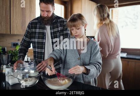 Familie mit kleiner Tochter Kochen drinnen, Winterurlaub in privater Wohnung. Stockfoto