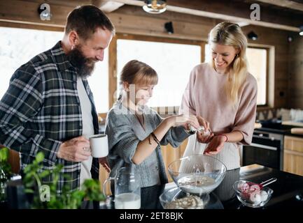 Familie mit kleiner Tochter Kochen drinnen, Winterurlaub in privater Wohnung. Stockfoto