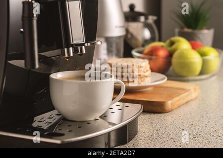 Moderne Espressomaschine mit einer Tasse im Inneren der Küche Nahaufnahme. Stockfoto