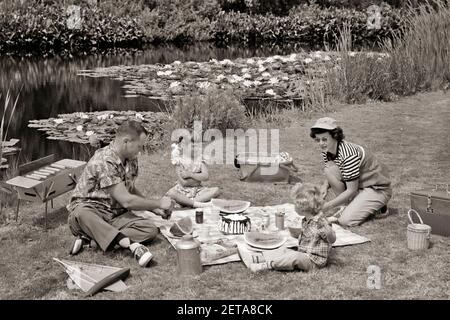 1950S FAMILIE MUTTER VATER UND ZWEI TÖCHTER IM SOMMER PICKNICK AM TEICH - C174 CRS001 HARS PAAR 4 SUBURBAN SONNENBRILLE MÜTTER ALTE ZEIT NOSTALGIE ALTE MODE SCHWESTER 1 JUVENILE STIL TEICH FAMILIEN FREUDE LIFESTYLE FEIER FRAUEN VERHEIRATET LÄNDLICHEN EHEPARTNER EHEMÄNNER GESUNDHEIT KOPIEREN RAUM FREUNDSCHAFT IN VOLLER LÄNGE HALBLANG DAMEN TÖCHTER PERSONEN SZENISCHE MÄNNER GESCHWISTER SCHWESTERN VÄTER B&W PARTNER SOMMERGLÜCK HOCH WINKEL ABENTEUER FREIZEIT UND VÄTER ERHOLUNG GESCHWISTER WASSERMELONE AL FRESCO SATTEL OXFORDS PICKNICKEN STILVOLLE ZUSAMMENARBEIT HOT DOGS JUVENILES MID-ADULT MID-ADULT MANN MITTLERER ERWACHSENER FRAU Stockfoto