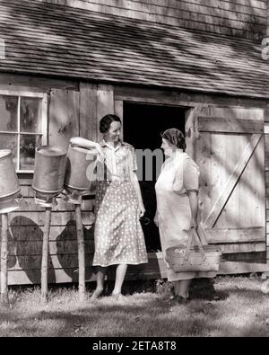 1930S ZWEI FRAUEN VERWICKELT IN GESPRÄCH NEBEN BAUERNHOF GEBÄUDE STEHEN STÖCKE MIT AUF DEN KOPF TROCKNENDEN METALLMILCHDOSEN KLATSCHEN - D4535 HAR001 HARS HOME LEBEN KOPIEREN RAUM FREUNDSCHAFT IN VOLLER LÄNGE DAMEN PERSONEN DOSEN LANDWIRTSCHAFT KOPF GESCHWISTER SCHWESTERN KLATSCH LANDWIRTSCHAFT B&W KLEIDER BUZZ GLÜCK TROCKNEN BAUERN BUSYBODY ERZÄHLEN ENGAGIERTE GESCHWISTER GESCHICHTEN VERBINDUNG NEBEN FREUNDLICHER TATTLER HÖRENSAGEN KOOPERATION MID-ADULT MID-ADULT FRAU PEGS GERÜCHTE ZWEISAMKEIT SCHWARZ UND WEISS KAUKASISCHE ETHNIE HAR001 ALTMODISCH Stockfoto