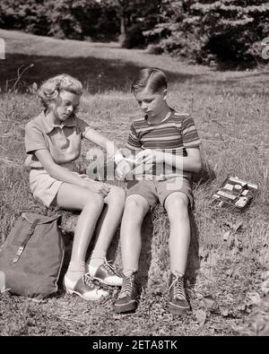 1930S 1940S WANDERER JUNGE MIT OFFENER VERBANDSZEUG-VERBANDSZEUG DER ARM EINES BLONDEN MÄDCHENS - F1508 HAR001 HARS FREUNDSCHAFT IN VOLLER LÄNGE FÜRSORGLICHE MÄNNER RISIKO TURNSCHUHE KIT HIKE S&W SOMMERZEIT HIGH ANGLE ABENTEUER FREIZEIT ERHOLUNG SATTELSCHUHE VERLETZEN SATTEL OXFORDS BANDAGING KONZEPTIONELLE ERSTE-HILFE ZWEIFARBIGE ZUSAMMENARBEIT WANDERER JUGENDLICHE PRE-TEEN PRE-TEEN JUNGE PRE-TEEN MÄDCHEN VORBEREITET SAISON LÖSUNGEN ZWEISAMKEIT RUCKSACK SCHWARZ UND WEISS KAUKASISCHE ETHNIZITÄT ERSTE HILFE HAR001 ALTMODISCH Stockfoto