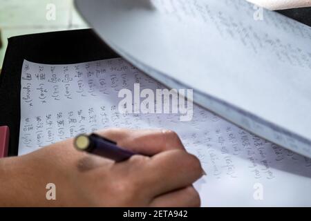 Chinesische Schriftzeichen werden auf weißem Papier niedergeschrieben Von einer menschlichen Hand mit einem treibenden Bleistift Stockfoto