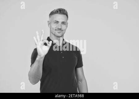 Alles ist OK. Schöner Mann zeigen OK gelben Hintergrund. Glücklicher Kerl lächeln mit Zufriedenheit. Einverstanden und akzeptabel. Vereinbarung und Genehmigung. Glücklich und zufrieden sein, Platz kopieren. Stockfoto