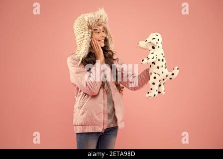 Angenehme Gedanken. Herbst Stil. Kindheit Glück. happy Kid rosa Hintergrund. Kleines Mädchen Dalmatiner Hund Spielzeug. kalten Jahreszeit in warme Kleidung Zubehör. Kid Mode. Hipster girl Fell winter earflap Hut. Stockfoto