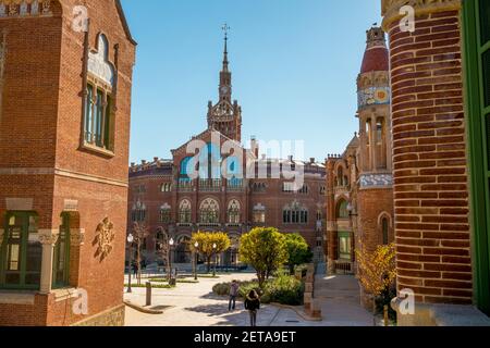 Blick durch einen Innenhof auf den Uhrenturm. Im Hospital de la Santa Creu i Sant Pau in Barcelona, Spanien. Stockfoto