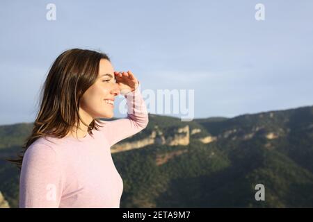 Profil einer glücklichen Frau, die sich mit Hand auf die Zukunft freut Stirn betrachtende Ansichten in den Berg Stockfoto