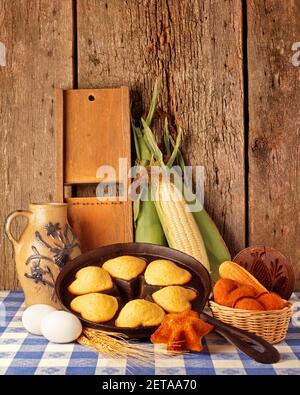 1970S LECKERE MAISMUFFINS IN HERZFÖRMIGEM GUSSEISEN GEBACKEN PFANNE KÜCHE STILLLEBEN MIT EIERN MILCHKRUG UND OHREN VON MAIS - KF15303 HAR001 HARS ALTMODISCH Stockfoto