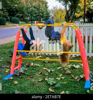 1970S JUNGE UND MÄDCHEN BRUDER UND SCHWESTER SPIELEN HÄNGEKLETTERN KOPFÜBER AUF AFFENRIEGEL IM HINTERHOF DURCH WEISSE PFOSTENLEISTE ZAUN - KJ4933 HAR001 HARS JUVENILE STREIKPOSTEN GESUNDE FREUND SICHERHEIT SPORTLER LIFESTYLE ZUFRIEDENHEIT FRAUEN BRÜDER GESUNDHEIT HEIM LEBEN LEICHTATHLETIK KOPIE RAUM FREUNDSCHAFT IN VOLLER LÄNGE HALBE LÄNGE KÖRPERLICHE FITNESS MÄNNER ATHLETISCHEN KOPF GESCHWISTER VERTRAUEN SCHWESTERN AKTIVITÄT GLÜCK KÖRPERLICHE ABENTEUER KRAFT UND AUFREGUNG FALLEN SAISON GESCHWISTER ATHLETEN FLEXIBILITÄT FREUNDLICH MUSKELN WACHSTUM JUGENDLICHE ZWEISAMKEIT HERBSTLICH KAUKASISCHE ETHNIZITÄT HERBST LAUB HAR001 AFFEN BARS ALTMODISCH Stockfoto