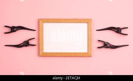 Banner Mockup Holzrahmen flach Lay von vier schwarzen Schnitt Haarclips der rechten und linken der Rahmenvorlage mit Kopierraum auf rosa Hintergrund. H Stockfoto