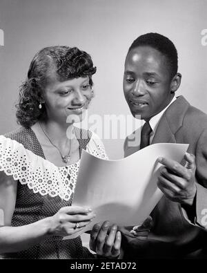 1950S AFRICAN-AMERICAN PAAR LESEN DOKUMENT ZERTIFIKAT DIPLOM FRAU TRÄGT GEPUNKTET SCHWEIZER KLEID MIT GROSSEM KRAGEN HERRENANZUG UND KRAWATTE - N696 HAR001 HARS STIL KOMMUNIKATION JUNGE ERWACHSENE INFORMATIONEN LIFESTYLE ZUFRIEDENHEIT FRAUEN STOLZES DIPLOM STUDIO SCHUSS KOPIE RAUM FREUNDSCHAFT HALBE LÄNGE DAMEN PERSONEN MÄNNER VERTRAUEN S & W ERFOLG ANZUG UND KRAWATTE GLÜCK DOKUMENT AFROAMERIKANER AFROAMERIKANISCH UND WISSEN SCHWARZ ETHNIZITÄT STOLZ VERBINDUNG STILVOLL GESTRICHELT SCHWEIZER ZERTIFIKAT GESTRICHELT SCHWEIZER ZWEISAMKEIT JUNGER ERWACHSENER MANN JUNGER ERWACHSENER FRAU SCHWARZ UND WEISS HAR001 ALTMODISCHE AFROAMERIKANER Stockfoto